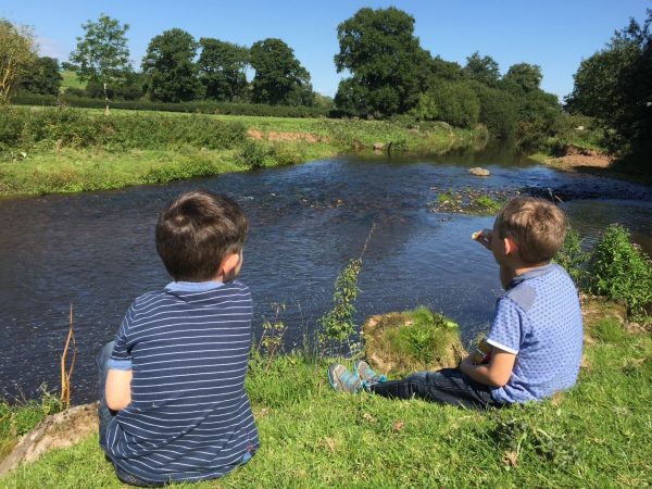 Children sat looking across the river in the Culm Valley